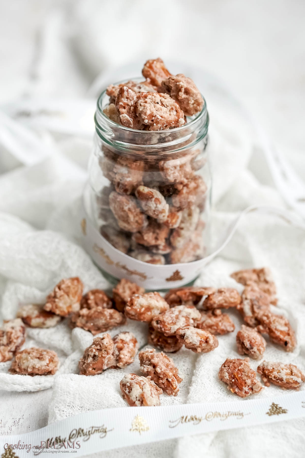 pralined almonds inside a jar and scattered on a white cloth.