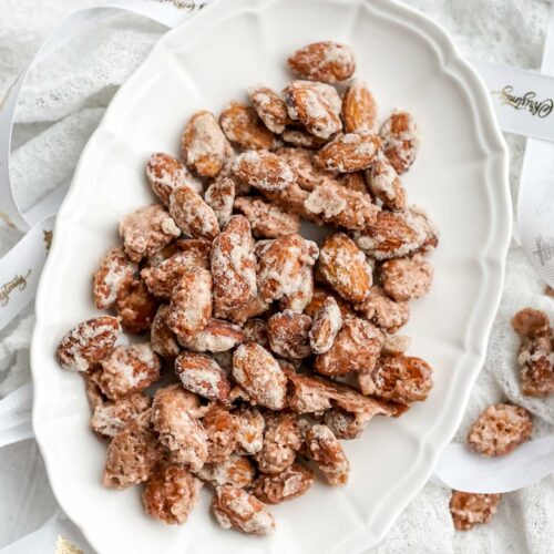 serving dish full of candied almonds on a white cloth.