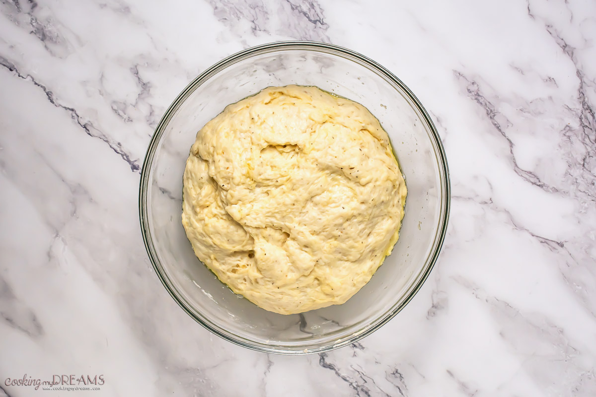 pizza dough rising in a bowl.