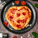 heart-shaped pizza on a black plate.