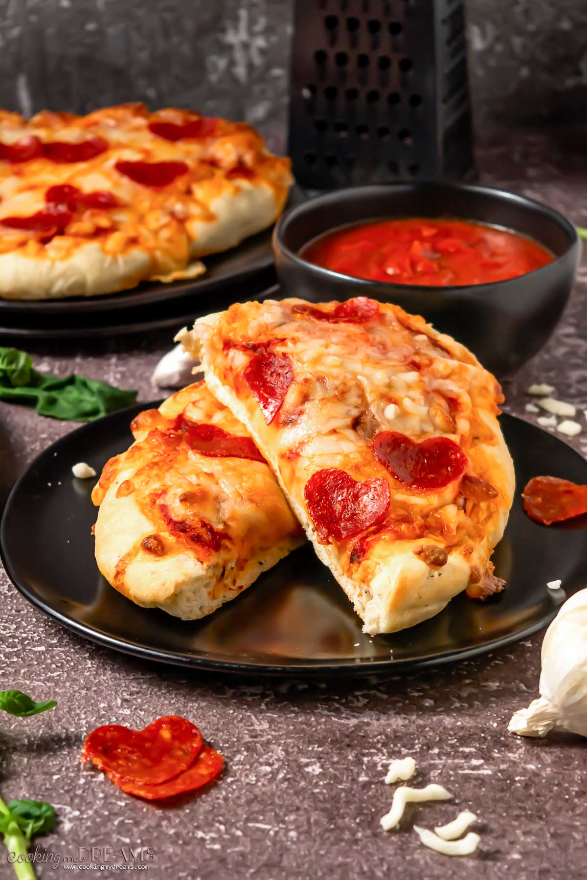 two pieces of pepperoni pizza on a black plate.