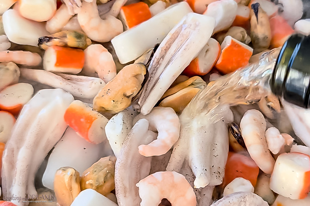 seafood sautèeing in a skillet with white wine.
