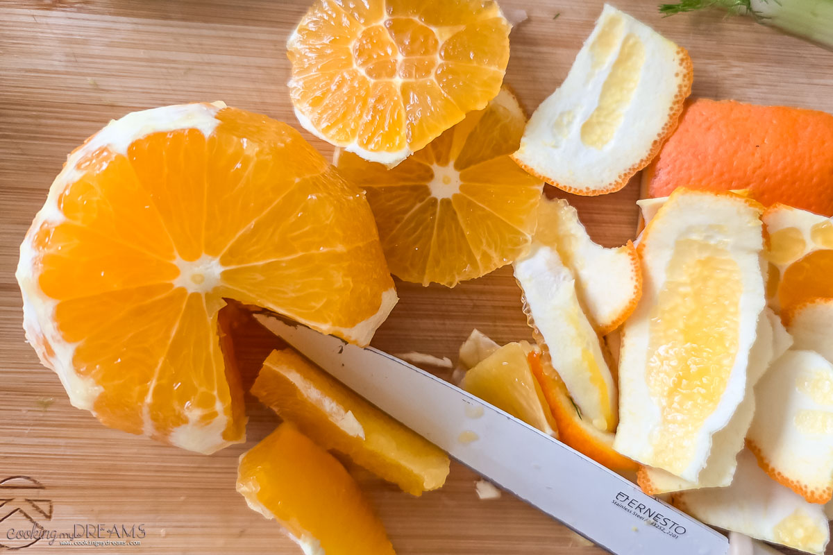 orange peeled and being sliced into sections on a cutting board.