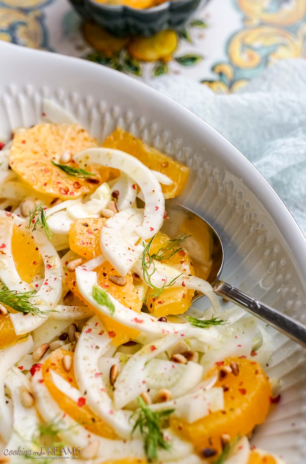 spoon digging into the orange fennel salad on a serving dish.