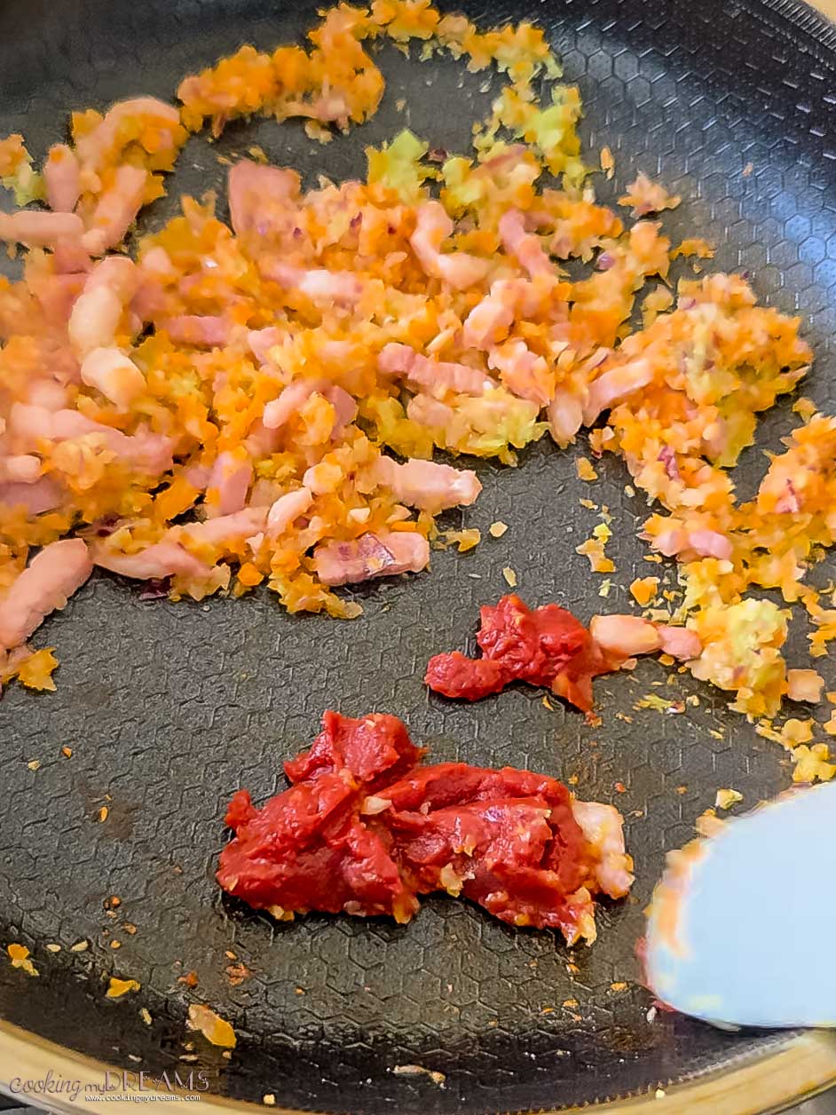 tomato paste is added to the skillet with the soffritto.