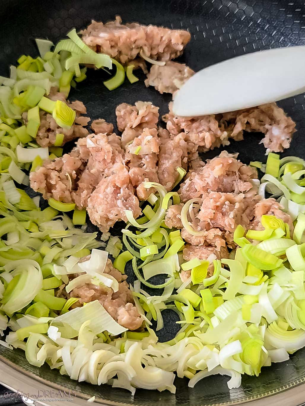 sausage and leek cooking in a skillet.