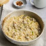 bowl with sausage and leek orzo on top of a towel.