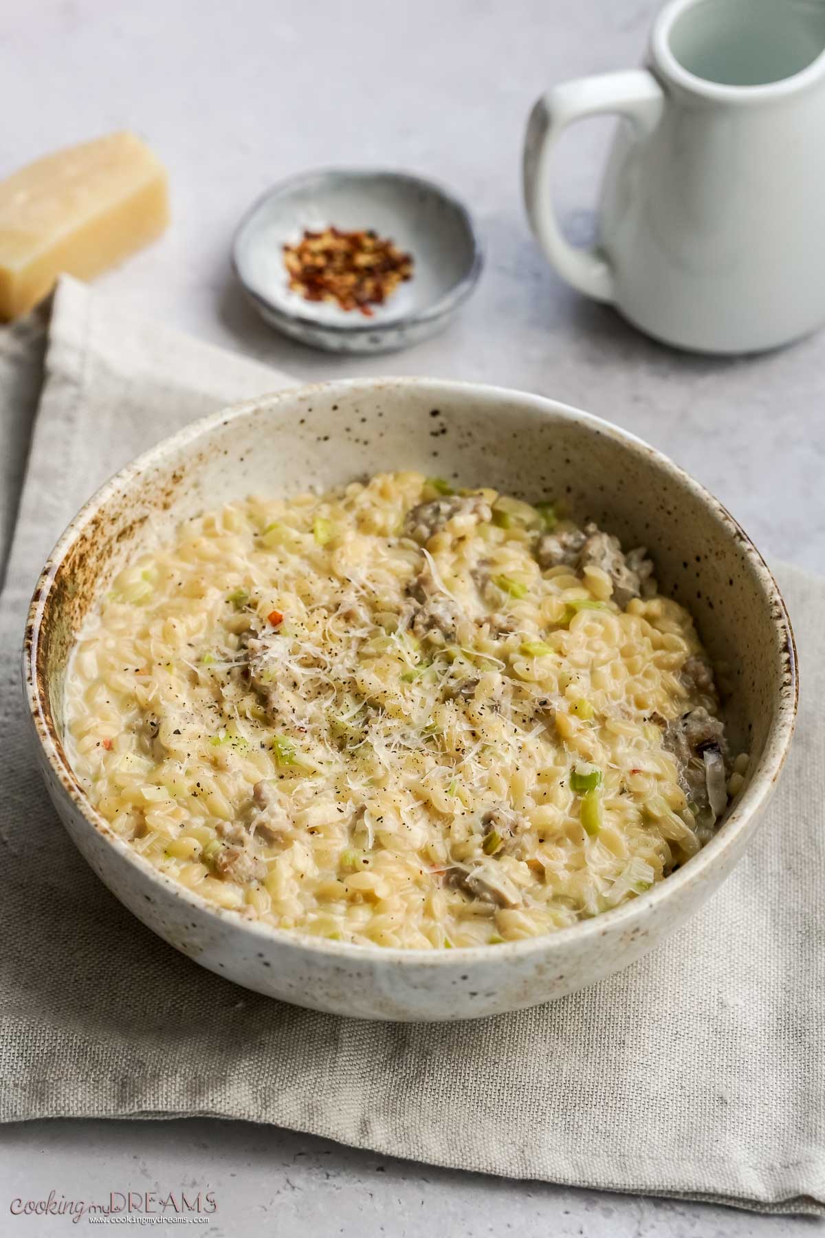 bowl with sausage and leek orzo on top of a towel.