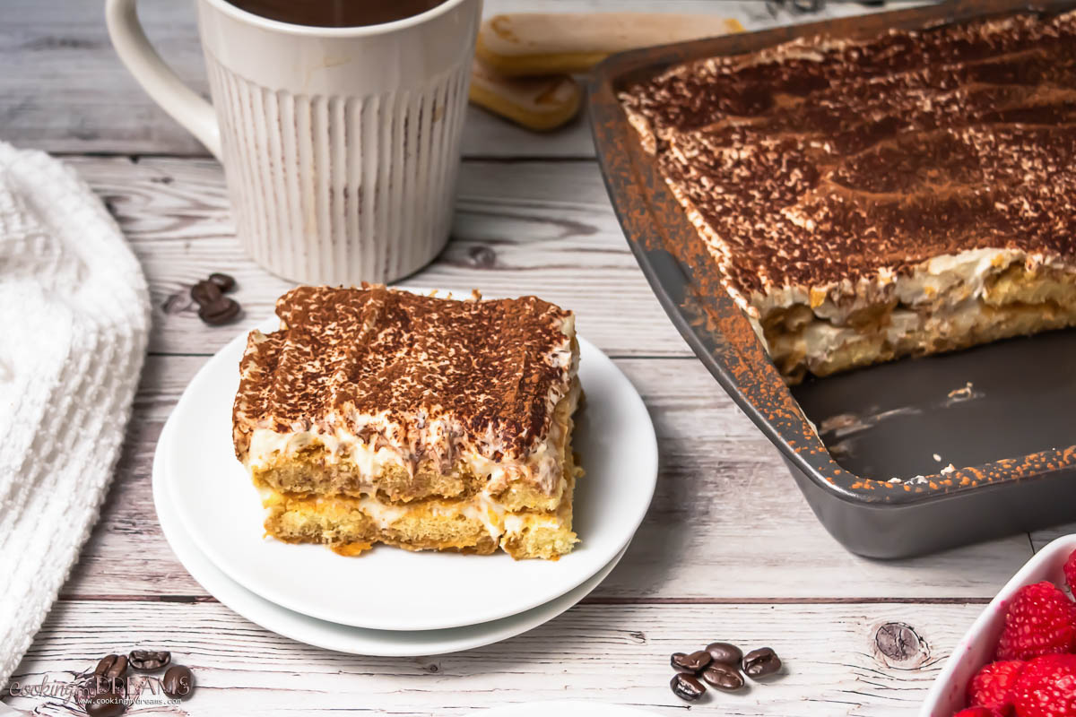 a portion of tiramisu on a plate next to the full tray.