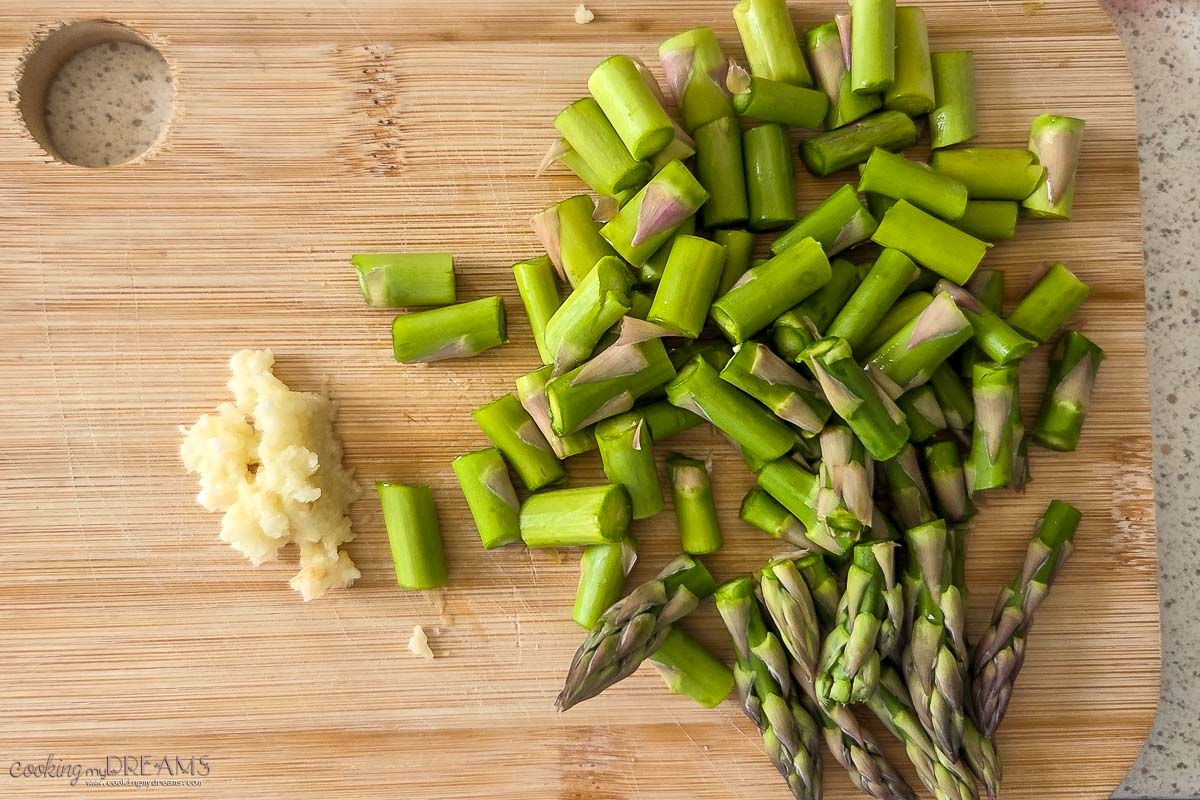 chopped asparagus and garlic on a cutting board.