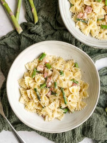 two bowls of creamy pasta with aspragus and pancetta.