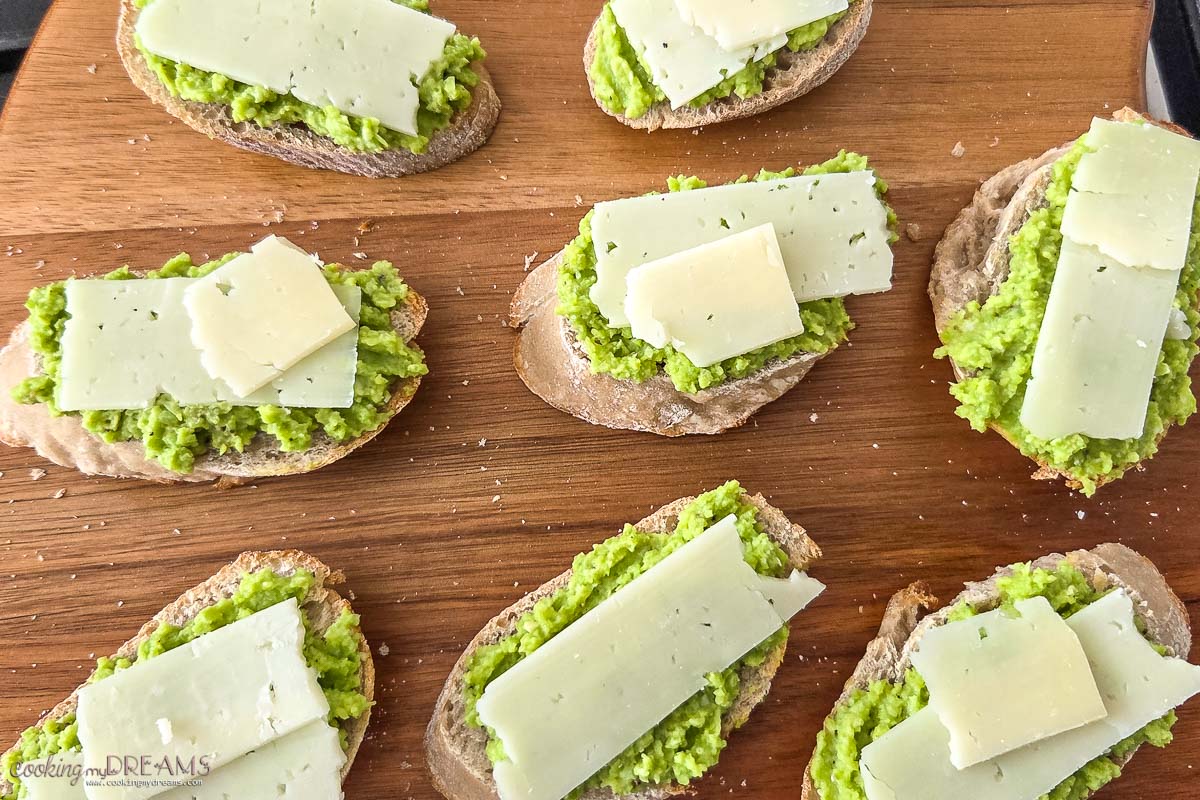 fava beans and pecorino cheese crostini on a wooden board.