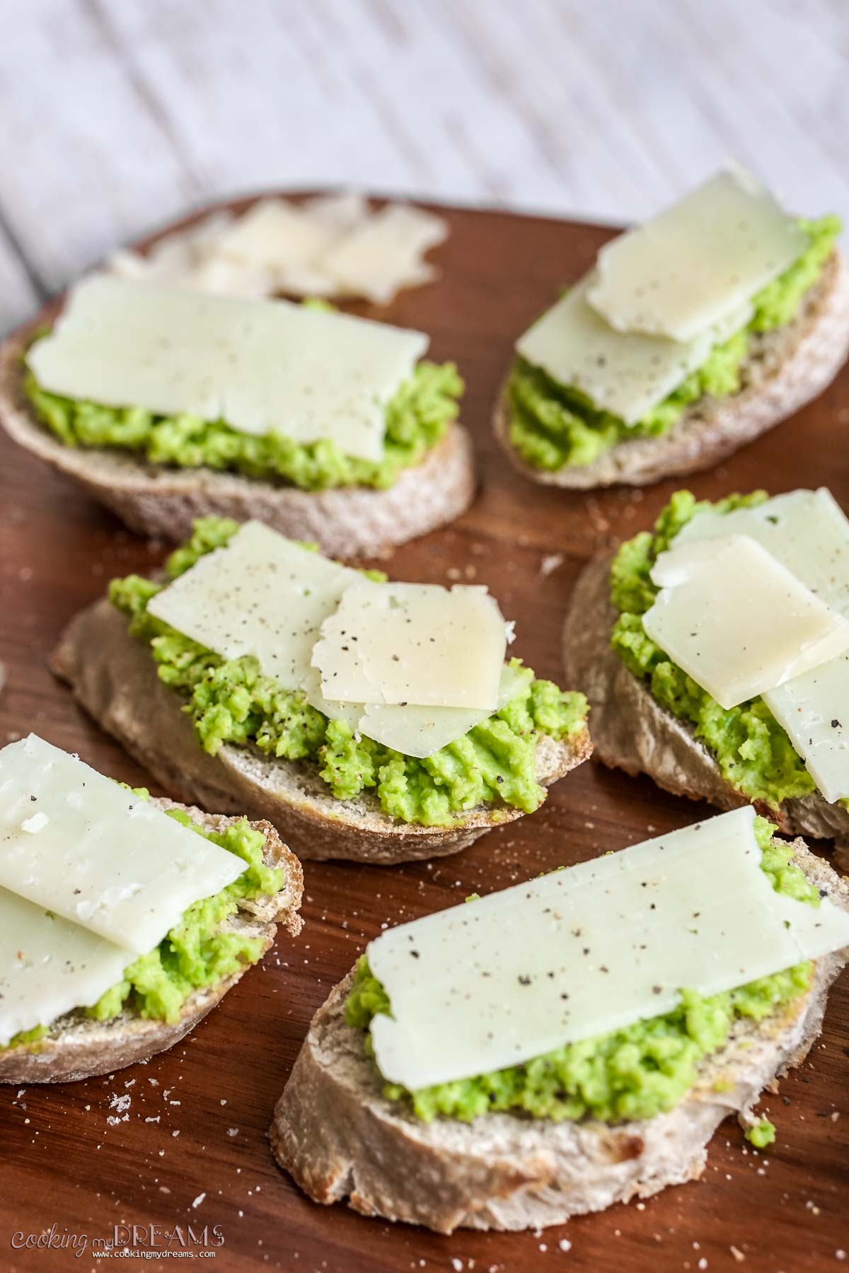 fava beans and pecorino cheese crostini on a wooden board.