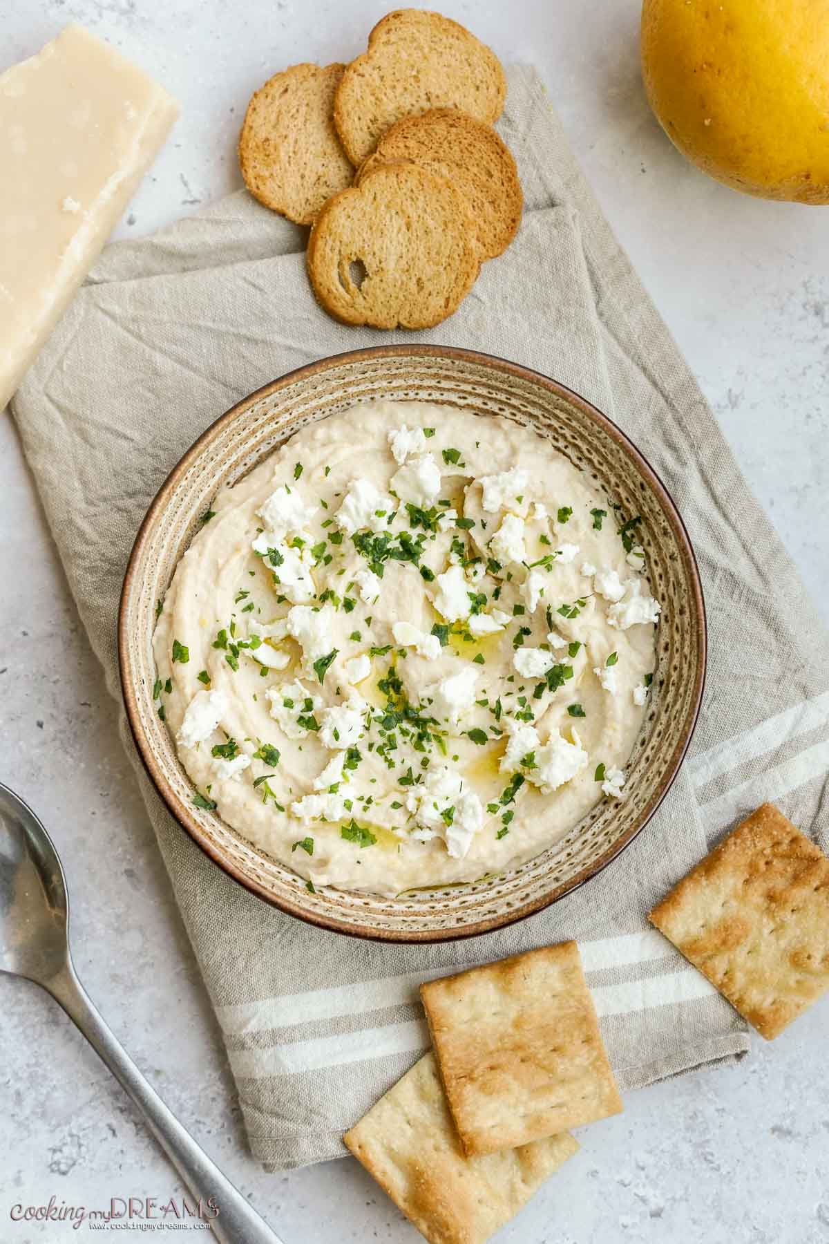 lemon feta white bean dip in a bowl surrounded by crackers.