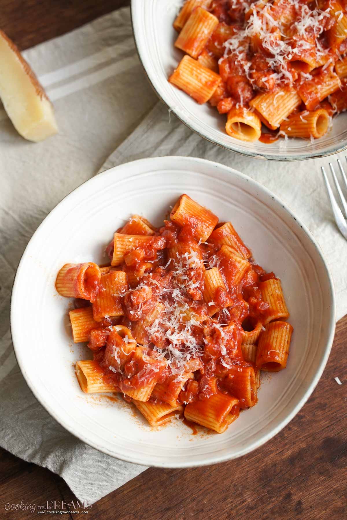 two bowls of rigatoni amatriciana on a table.