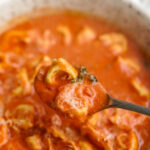 spoon picking up a bite of tomato tortellini soup.