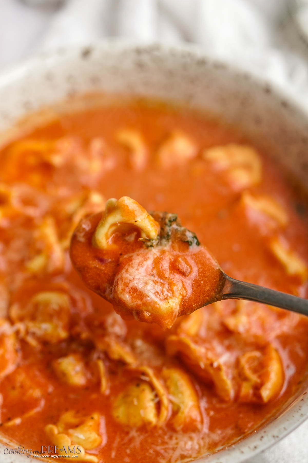 spoon picking up a bite of tomato tortellini soup.