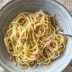 spaghetti with butter and tuna in a bowl with a fork.