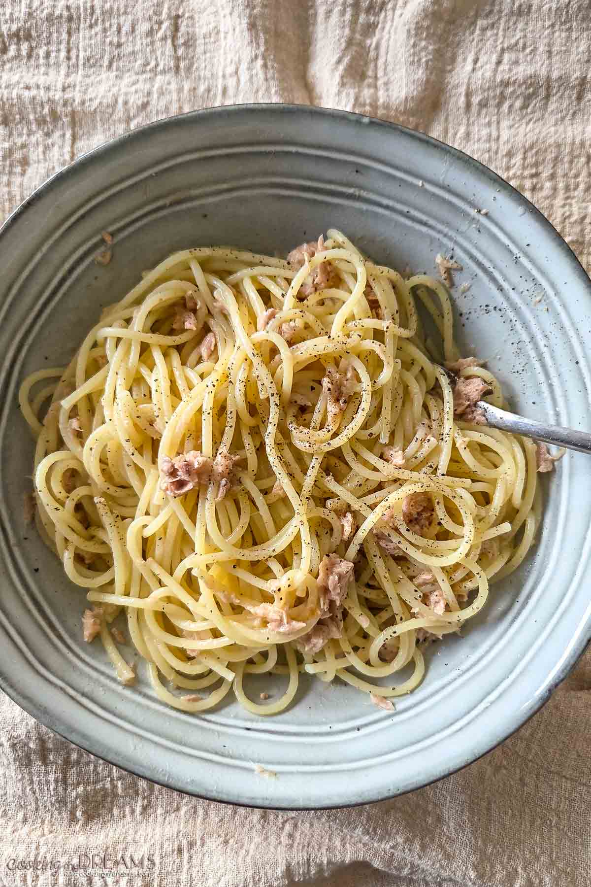 spaghetti with butter and tuna in a bowl with a fork.
