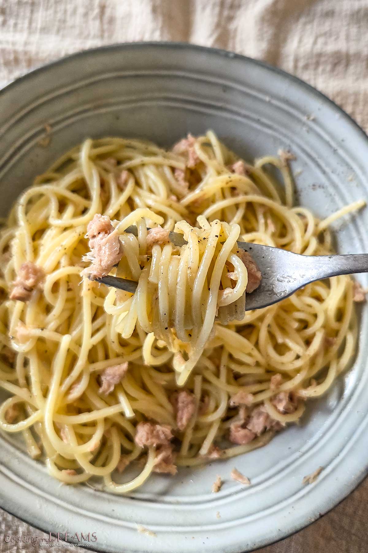 fork lifting a bite of spaghetti with butter and tuna.