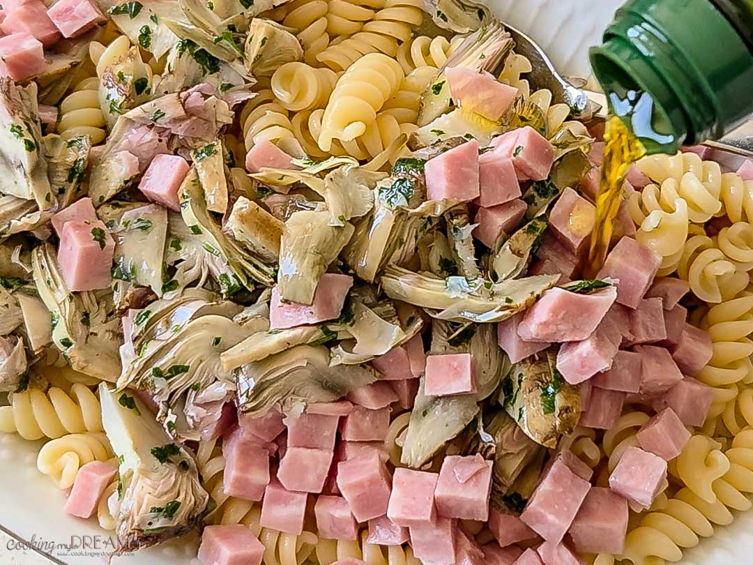 olive oil is added to the pasta and then mixed.