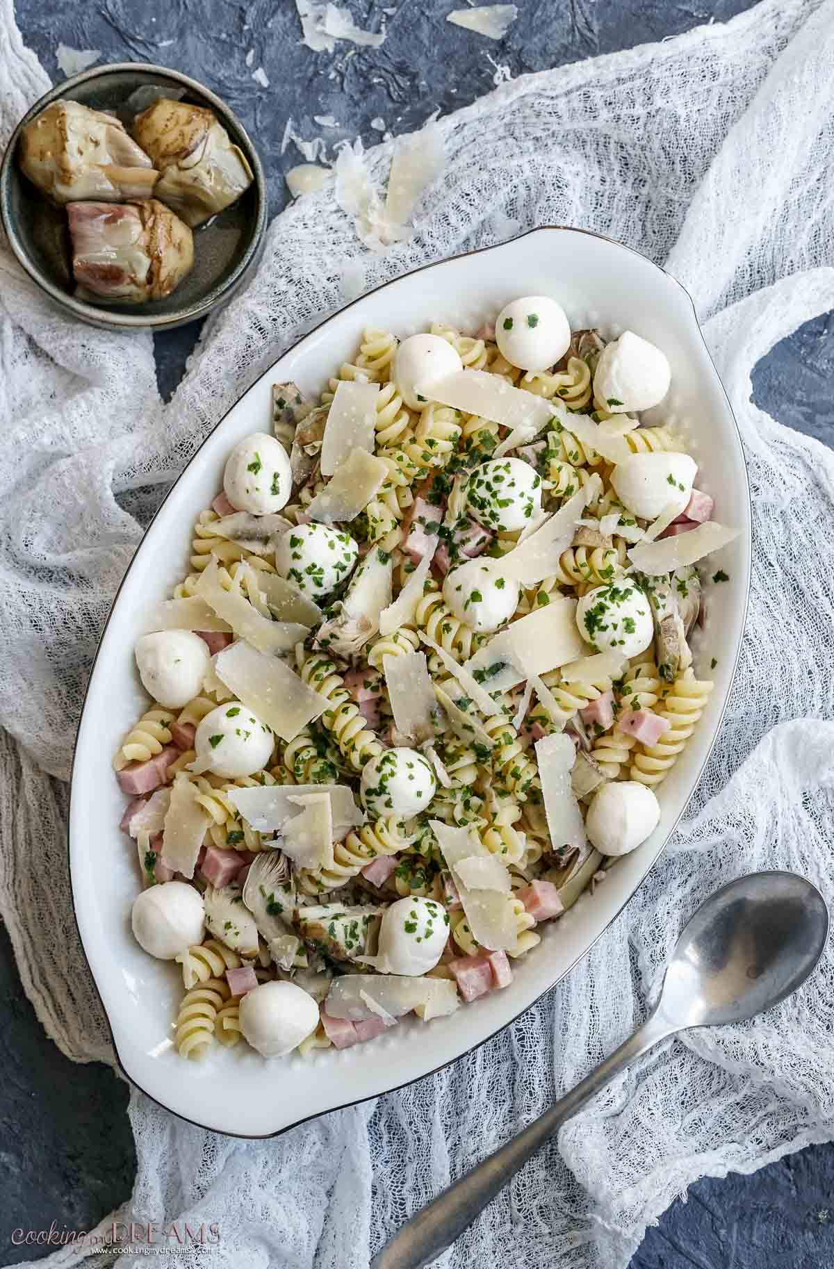 oval platter with marinated artichokes pasta salad.
