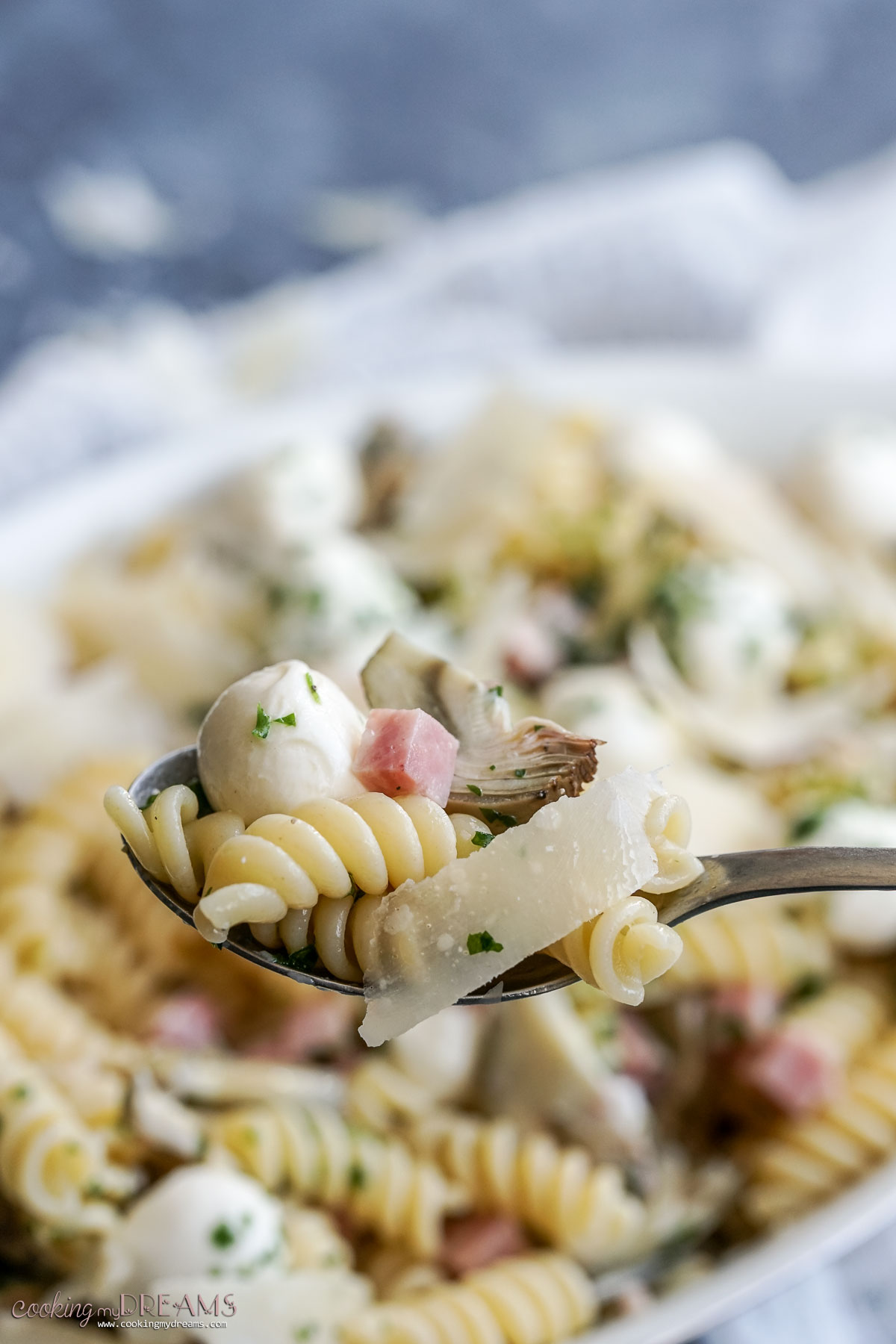 spoon taking a bite of artichoke pasta salad.