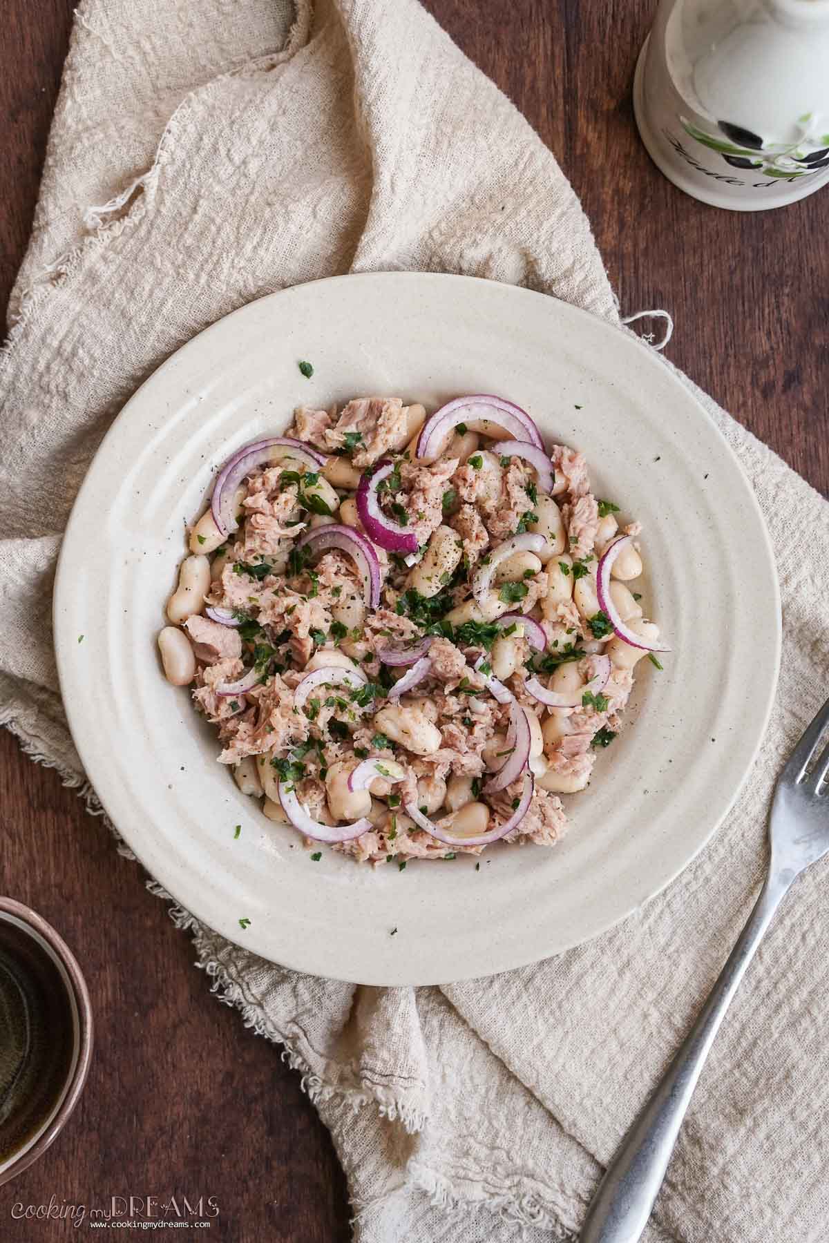 plate with tuna white bean salad on a table.
