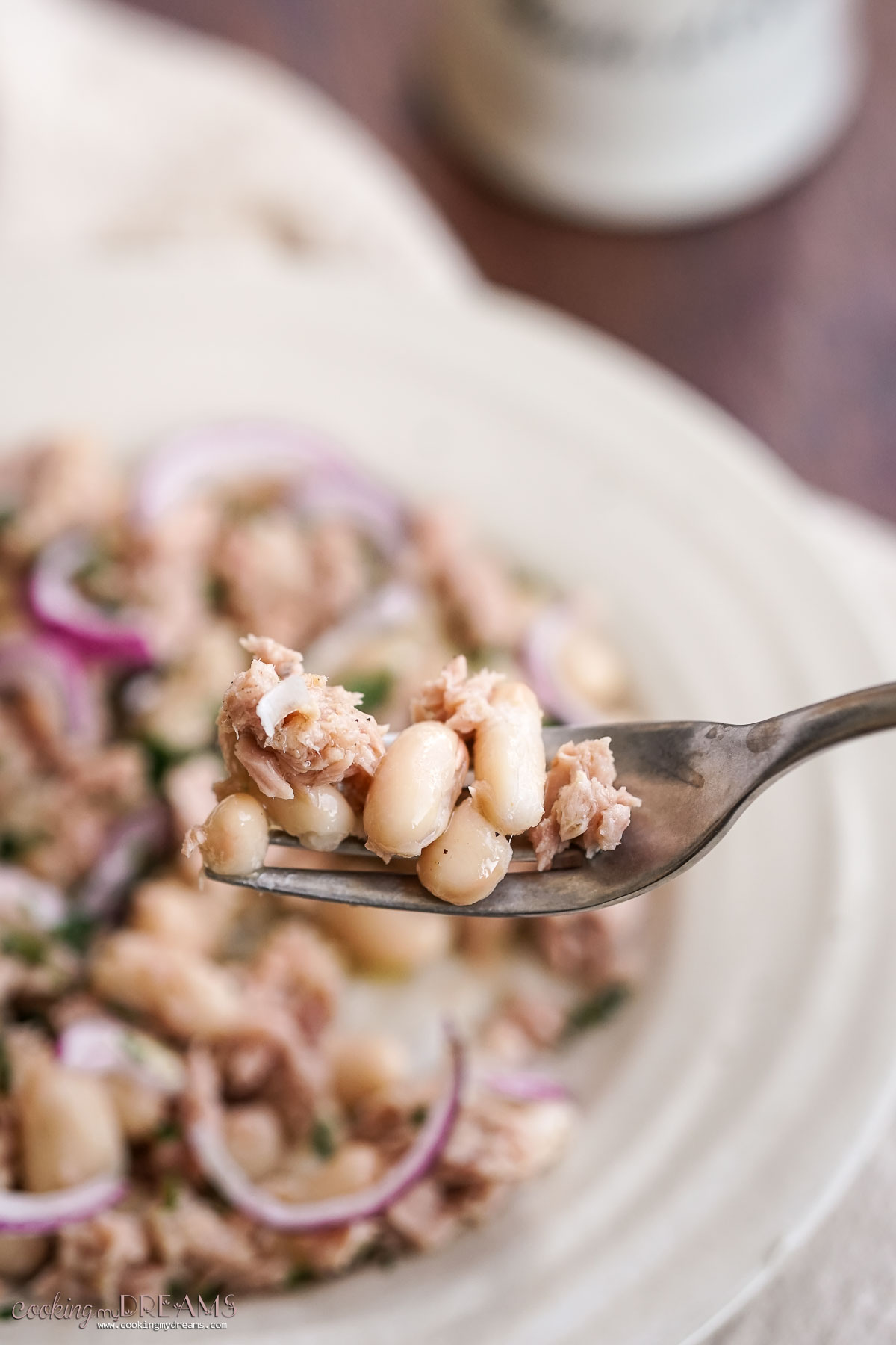 fork holding a bite of cannellini bean and tuna salad.