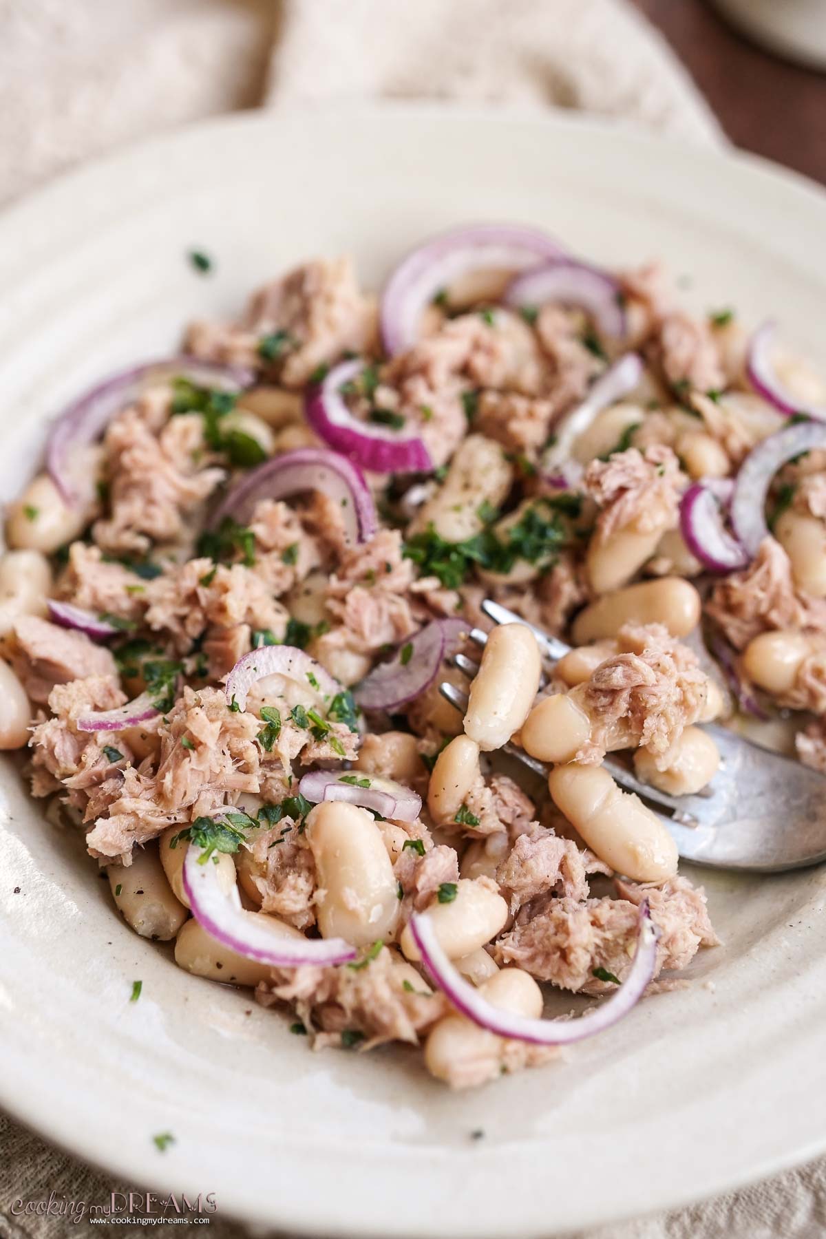 fork digging into the white bean tuna salad.