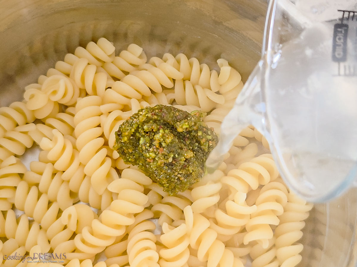 pasta water added to the pot with pistachio pesto and pasta.