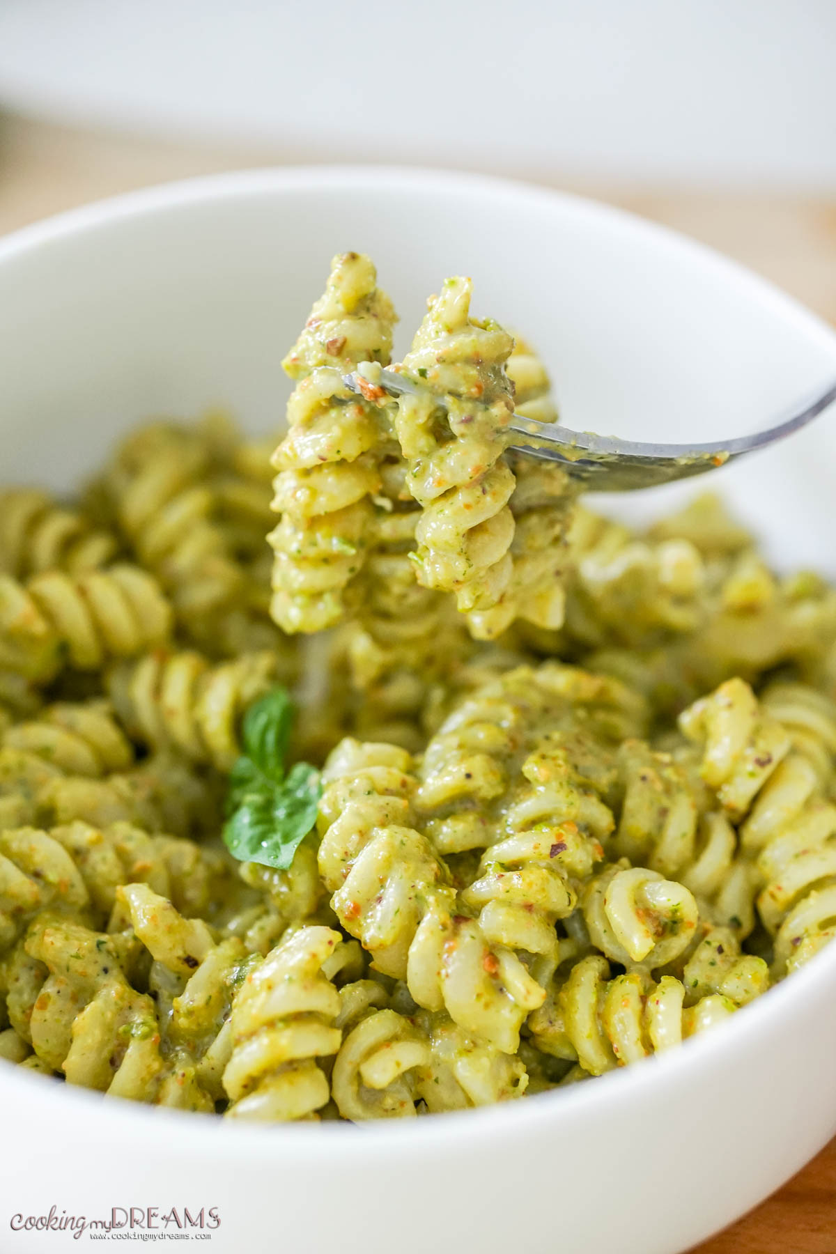 forking lifting a bite of pasta with creamy pistachio pesto.