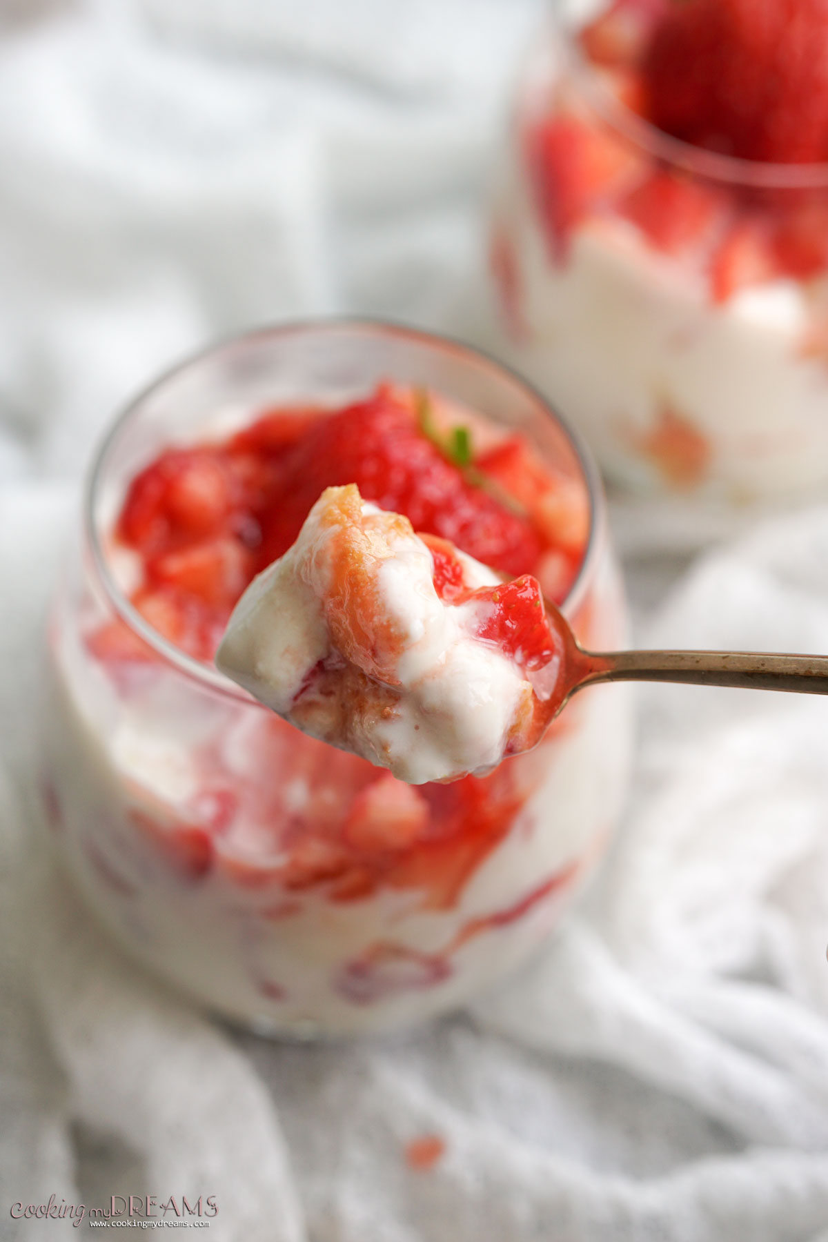 spoon taking a bite of ricotta strawberry parfait.