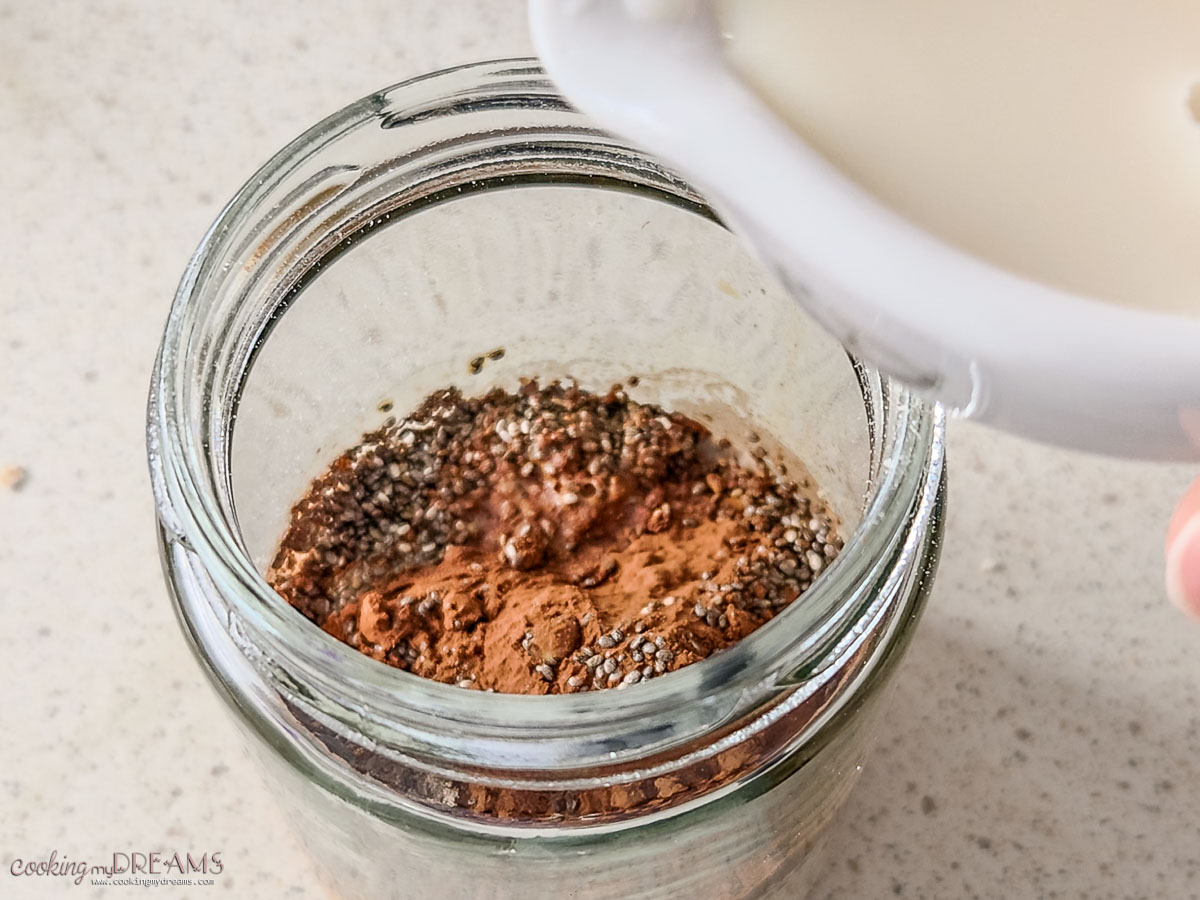 adding milk to the ingredients in a jar.