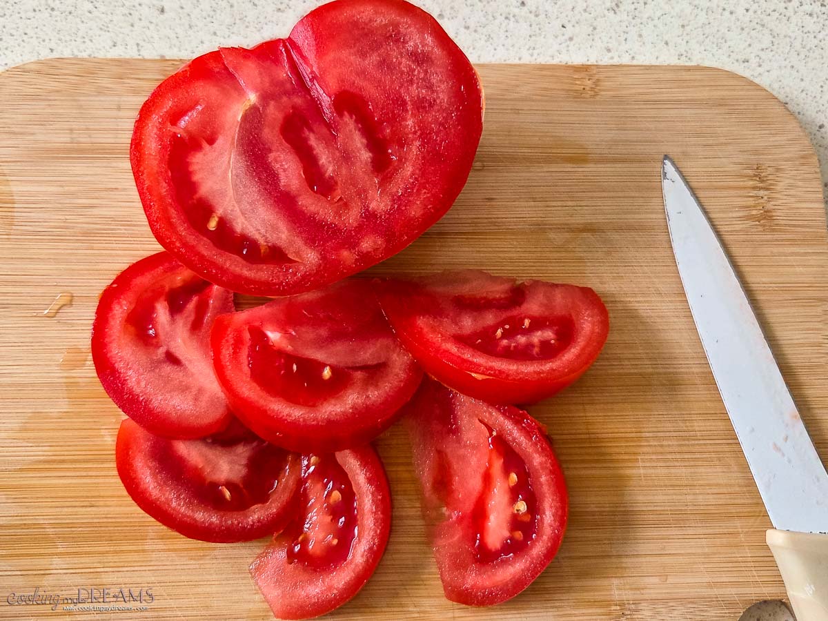 knife slicing tomatoes on a cutting board.