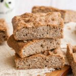 stack of squares of whole wheat focaccia on a towel.