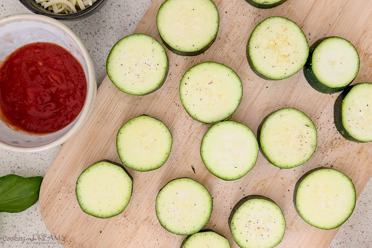 zucchini slices seasoned on a cutting board.