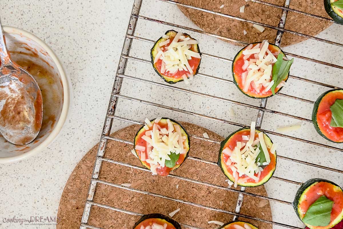 zucchini pizza bites on a baking rack ready for the oven.