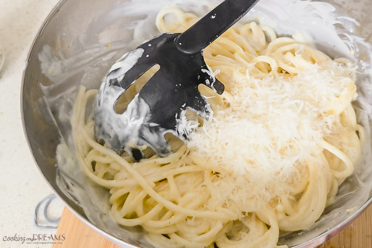 mixing parmesan cheese into the lemon pasta.